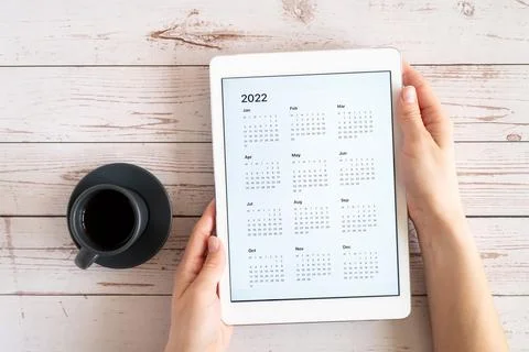 Tablet computer with an open app of calendar for 2022 year and cup of tea or  Stock Photos