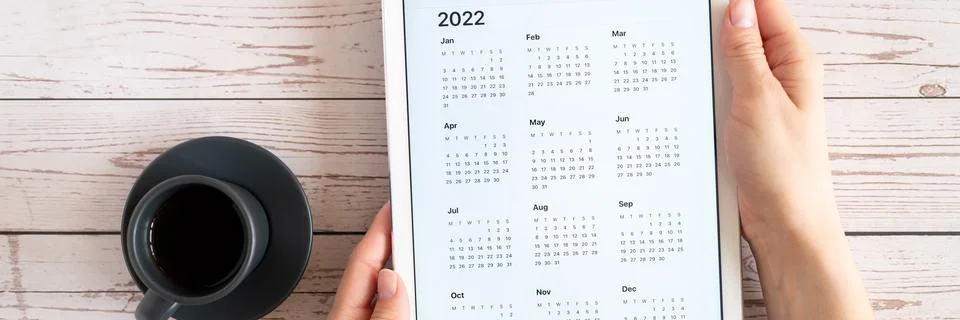 Tablet computer with an open app of calendar for 2022 year and cup of tea or  Stock Photos