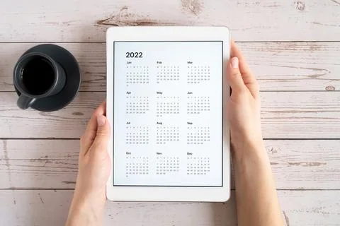 Tablet computer with an open app of calendar for 2022 year and cup of tea or  Stock Photos