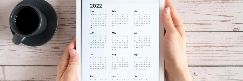 Tablet computer with an open app of calendar for 2022 year and cup of tea or  Stock Photos