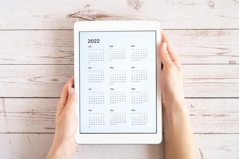 Tablet computer with an open app of calendar for 2022 year in a womans hands  Foto stock