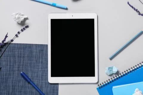 Tablet computer with pens, lavender flowers and notebooks on grey background Stock Photos