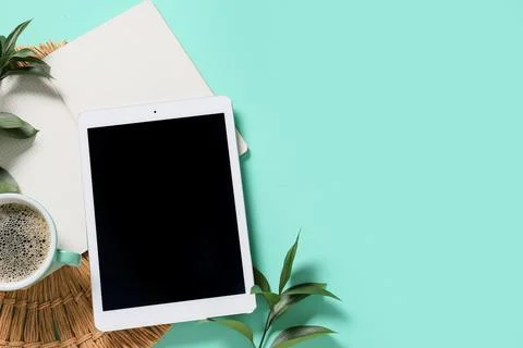 Tablet computer with plant branches, notebook and cup of coffee on turquoise  Stock Photos
