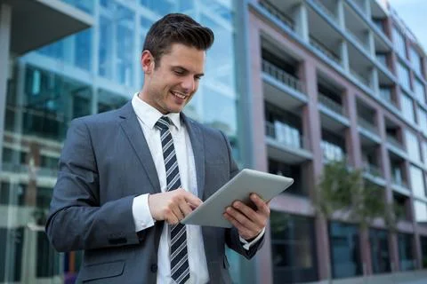 Tablet computer resting on concrete plaza beside glass-and-steel office building Stockfoto's