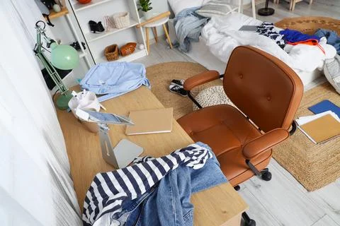 Tablet computer with scattered clothes on table in messy teenager's room, top Stock Photos