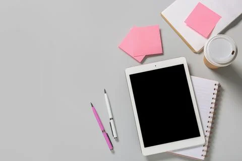 Tablet computer with takeaway cup of coffee, notebooks, pens and sticky notes Stock Photos
