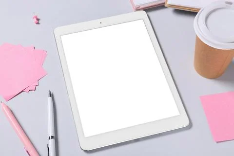 Tablet computer with takeaway cup of coffee, sticky notes and pens on grey ba Stock Photos