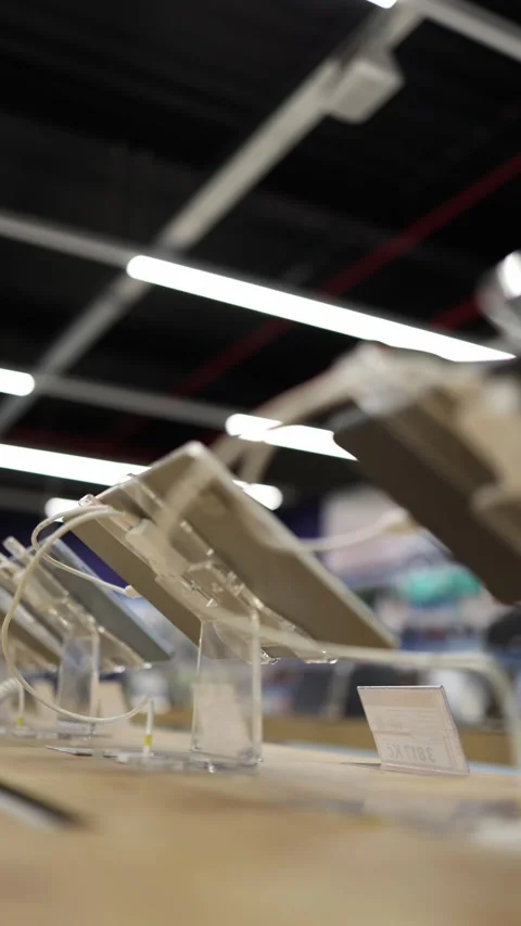 Tablet computers displayed on security stands inside an electronics store Stock Footage 345357839
