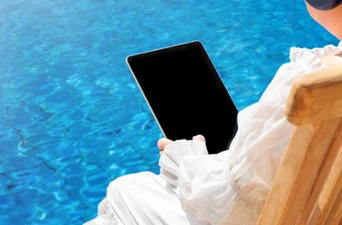 A tablet with copy space in the hands of a child sits near the water Stock Photos