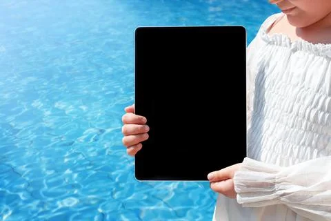 Tablet with copy space in the hands of a child near the pool Stock Photos
