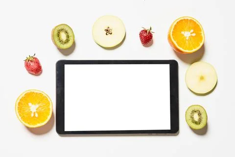 Tablet with empty white screen and various fruits slices around it Stock Photos