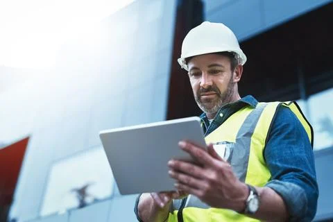 Tablet, engineer and man with helmet on construction site for development or Stock Photos
