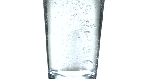 Tablet falling and dissolving into a glass of water against white background Stock Footage 234885778