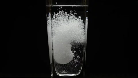 Tablet is falling and sparkling in a glass of water on the black background Stock Footage 166039313