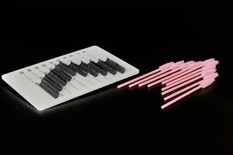 A tablet with false eyelashes and brushes on a black background. Stock Photos