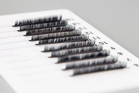 A tablet with false eyelashes on a gray background. Stock Photos