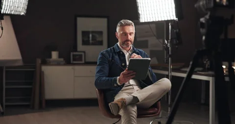 Tablet, filming and man on set reading script for documentary interview or Stock Footage 303539349