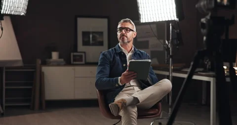 Tablet, filming and man on set with lights reading for documentary interview or Stock Footage 303615917