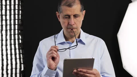 Tablet, filming and man on set with lights reading for documentary interview Stockbeeldmateriaal 332677989