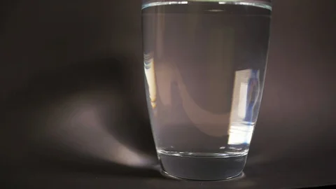 Tablet form bath salt fall slowmotion in vase with decomposition reaction water Stock Footage 114747986
