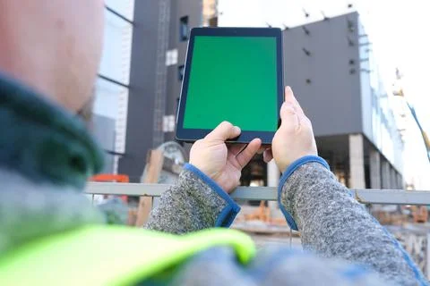 Tablet with green screen against the backdrop of a building under constructio Stock Photos