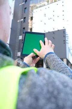 Tablet with green screen against the backdrop of a building under constructio Stock Photos