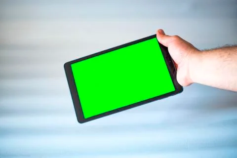 Tablet with green screen fastened with one hand on white background. Stock Photos