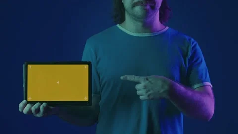 A tablet with a green screen in a man's hand in a studio in pink and green neon Stock Footage 252016889