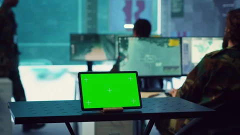 Tablet with greenscreen display running in a command post base of operations Stock Footage 276908133