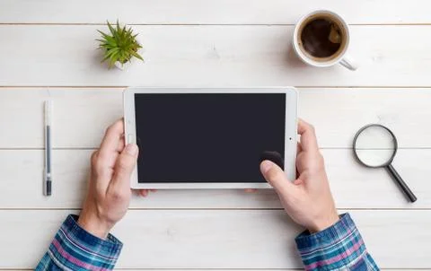 Tablet in hand mockup on work desk. Top view, flat lay composition. Close-up. Stock Photos