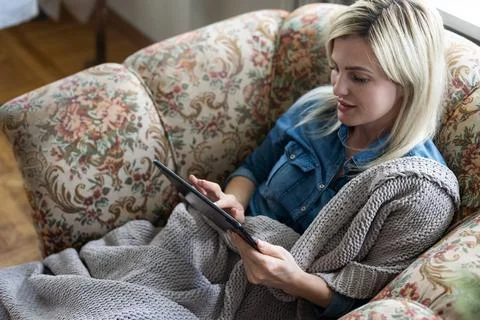 Tablet in the hands of women. Light background. Blue jeans Stock Photos