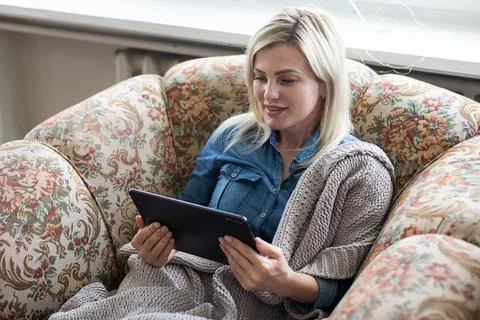 Tablet in the hands of women. Light background. Blue jeans Stock Photos