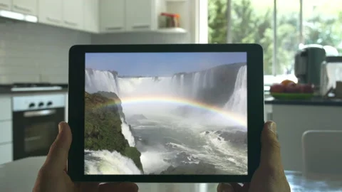 Tablet held by hands. Falls Cinemagraph. Close up. Modern kitchen, day. Looped Stock Footage 131243584