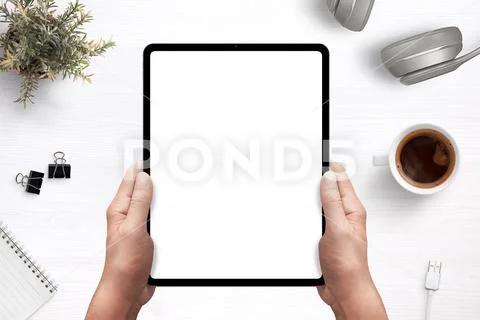 Tablet in man hands mockup above work desk with separated layers PSD Template