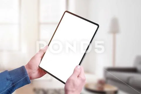 Tablet in man hands mockup in vertical position. Home interior in background PSD-Vorlage