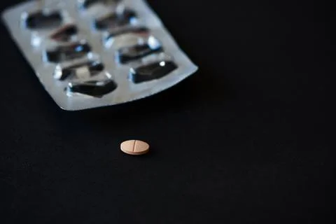 A tablet of medication on black background Stock Photos