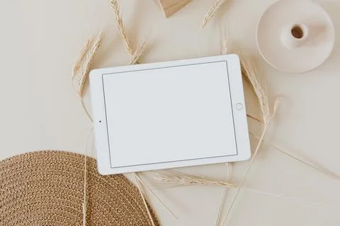 Tablet pad on beige background with wheat / rye stalks and wicker napkin. Fla Stock Photos