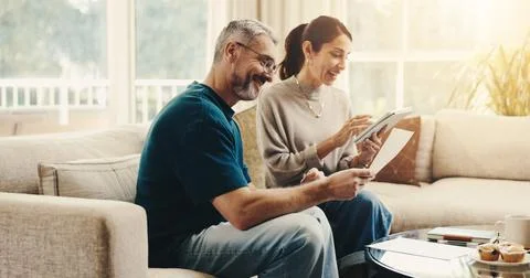 Tablet, paperwork and couple on sofa in home with planning budget, savings or Stock Photos