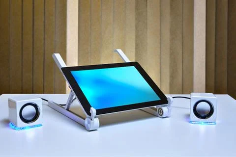 Tablet PC is connected to small external speakers. Stock Photos