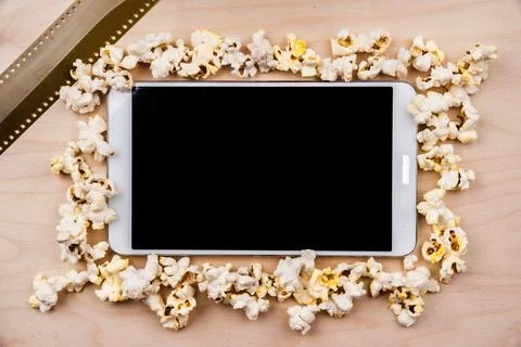 Tablet pc on dark background with attributes of cinema. Visual metaphor for.. Stock Photos