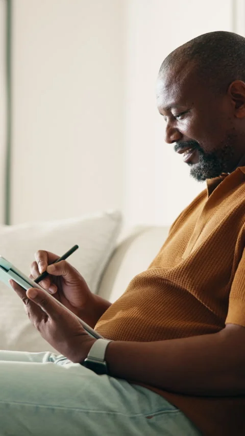 Tablet, pen and black man on sofa in home for remote work with web development 库存影片 337990461