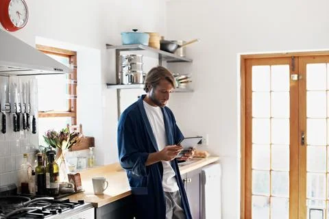 Tablet, reading and man in kitchen for online connection, social networking and Stock Photos
