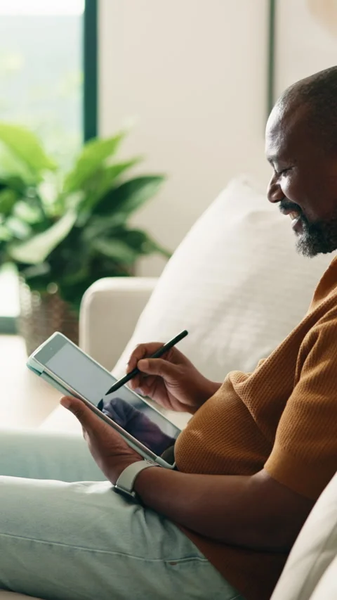 Tablet, relax and black man on sofa in home for remote work with web development 库存影片 338010367