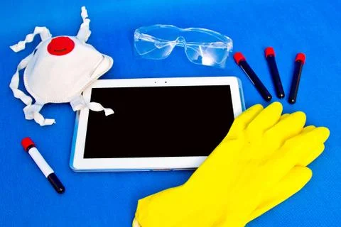 Tablet with rubber gloves test tubes and face mask top view. The concept of m Stock Photos