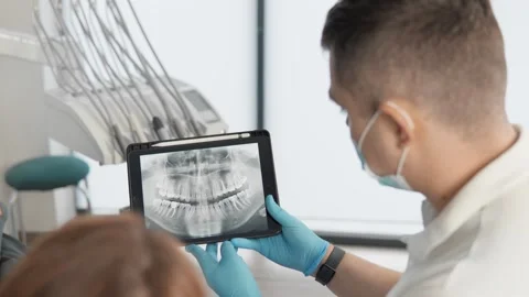 The tablet screen displays X-rays and diagnostic images, which the dentist Stock Footage 272643241