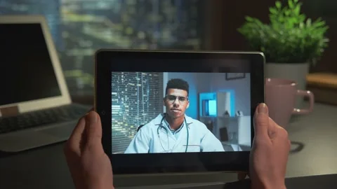 Tablet screen with handsome multiracial doctor speaking with patient online Video stock 157568290