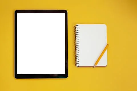 Tablet screen mockup and notepad isolated on yellow background, top view Fotos Stock