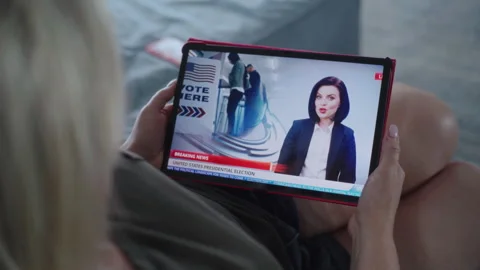 Tablet screen shows news broadcast about US elections with female newscaster Stock Footage 279897337