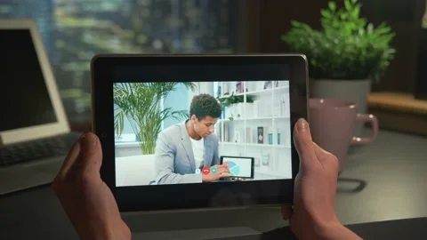 Tablet screen with video call: mixed-race man showing charts and explaining Stock Footage 157595645