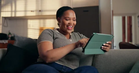 Tablet, scroll and laugh with black woman on sofa for ebook subscription, relax Stock Footage 329354418